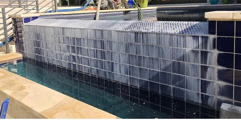 Before: streaky calcium buildup on deep navy waterline tile