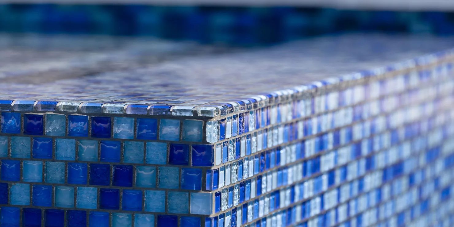 Close-up of blue glass mosaic waterline tile on a pool corner