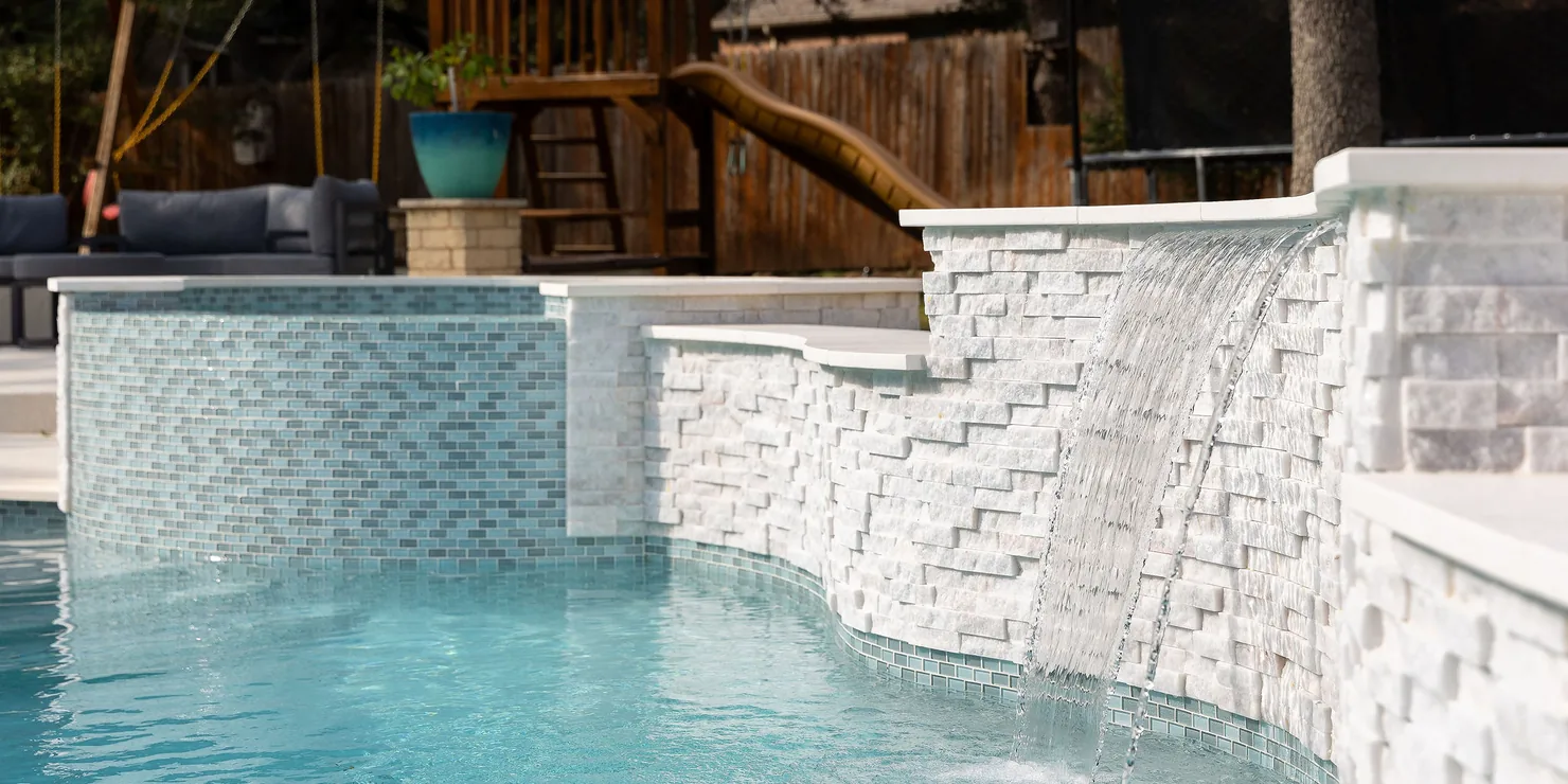 Renovated pool with a stacked-stone waterfall wall and new waterline tile