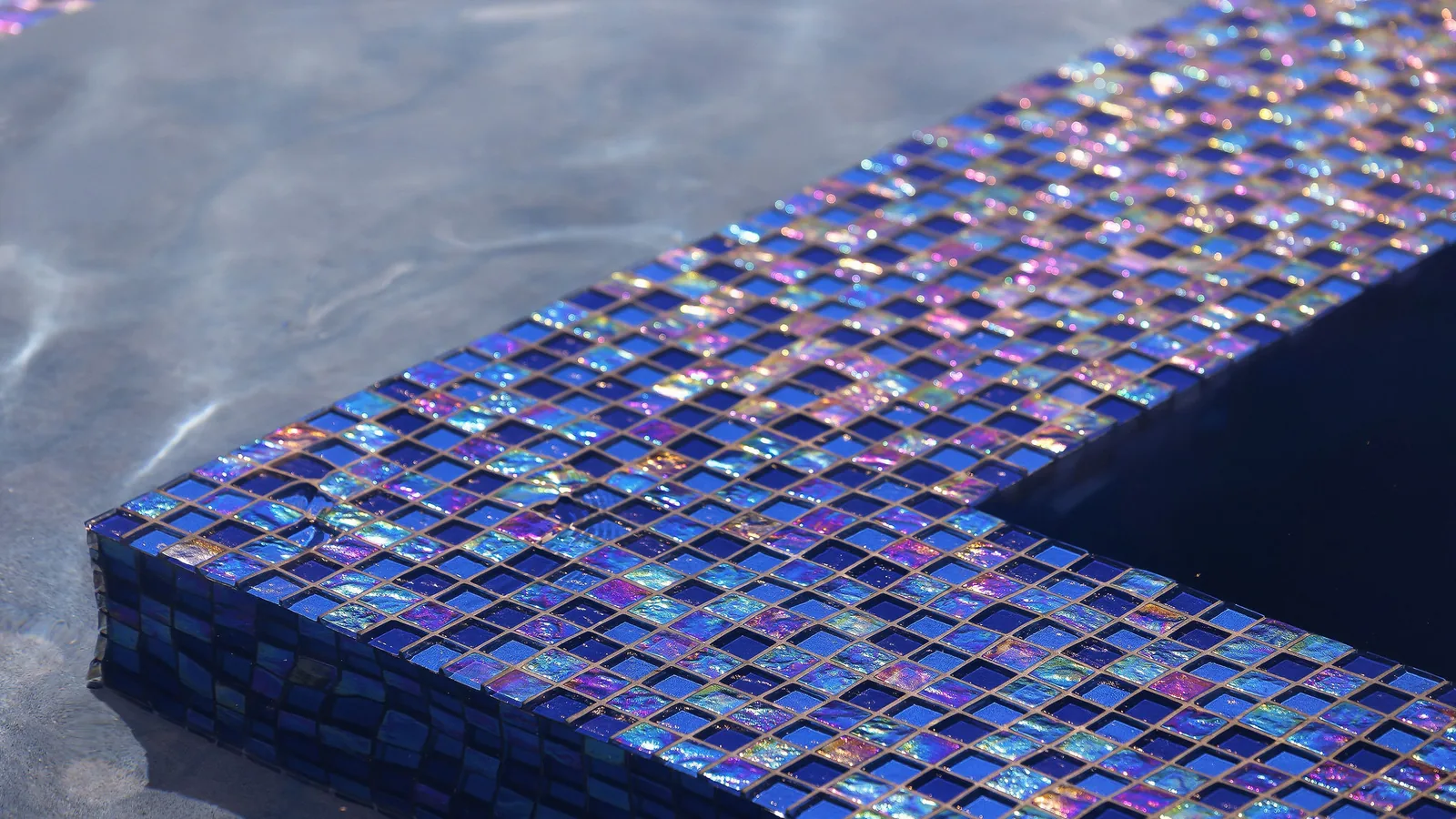Close-up of iridescent blue glass waterline tile catching sunlight