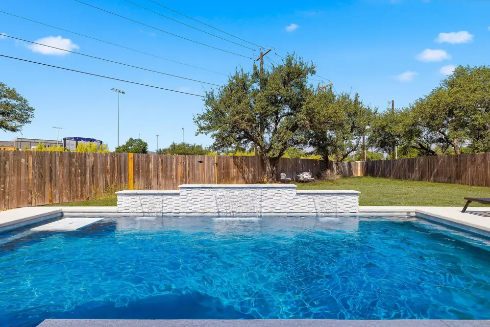 Pool with Hill Country trees and a serviced equipment area