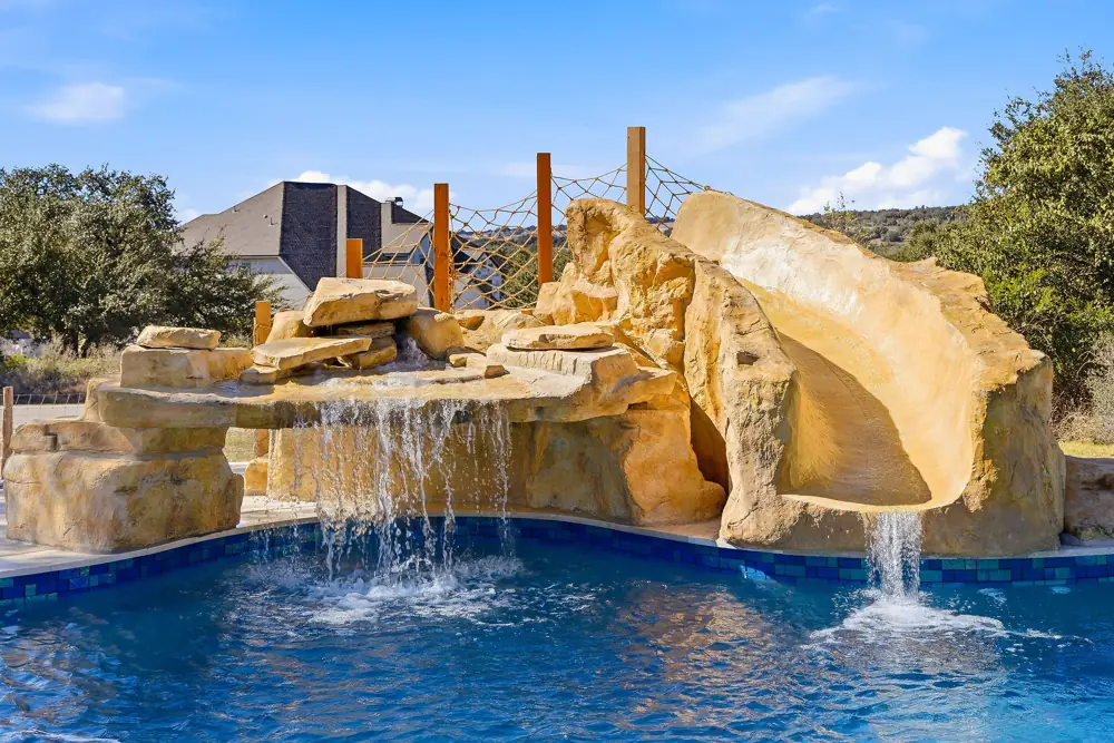 Rock waterfall and slide feature at a repaired backyard pool