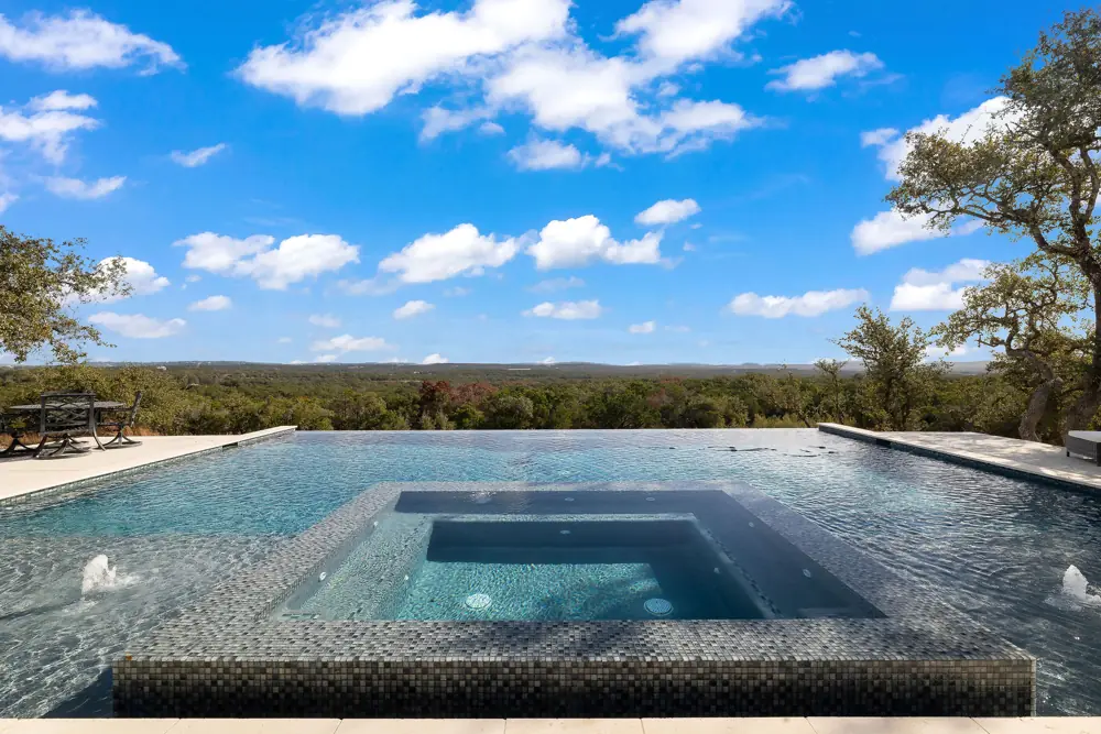 Dramatic infinity-edge pool with repaired waterline under a bright sky