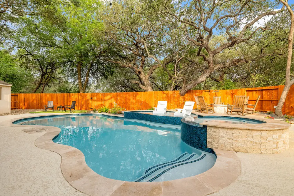 Renovated free-form pool and raised spa with string lights and stone decking