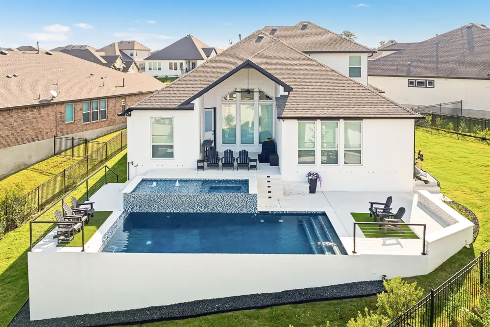 Aerial view of a renovated infinity-edge pool behind a modern home