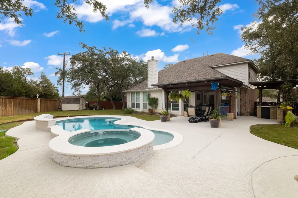 Kidney-shaped pool and spa with repaired tile at a white home
