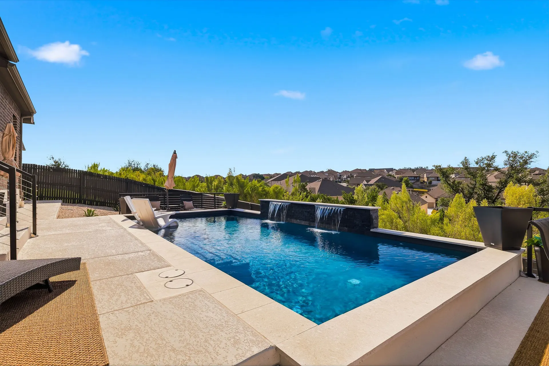Renovated pool with a stacked-stone waterfall wall overlooking the Texas Hill Country