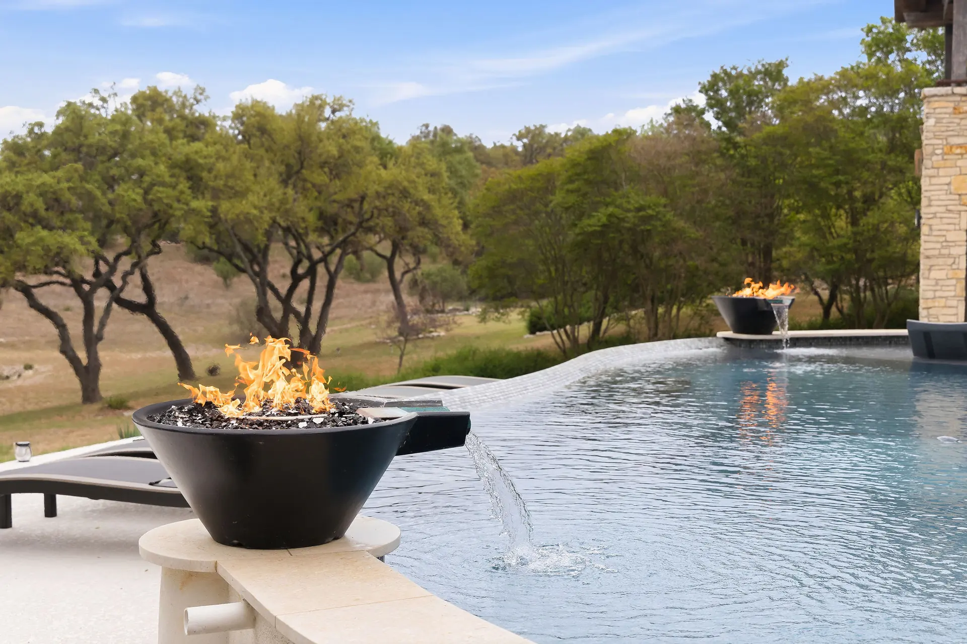 Dual fire bowl infinity pool with a Hill Country view near Spring Branch